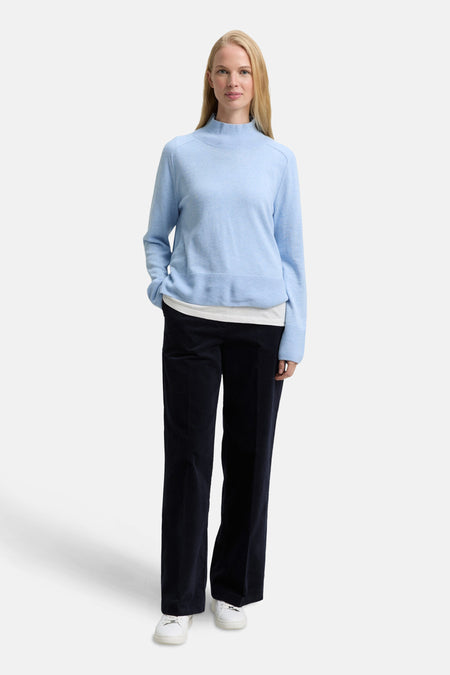 Blauwe broek van Tom Tailor, van corduroy, gedragen met een lichtblauwe trui en witte sneakers.