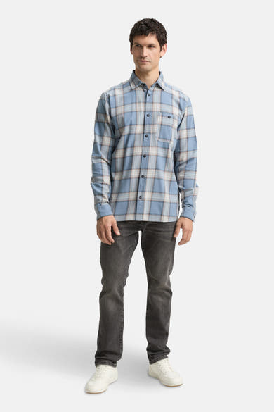 Chemise à manches longues bleue de Tom Tailor, à carreaux avec poche poitrine, portée avec un jean gris foncé et des baskets blanches.