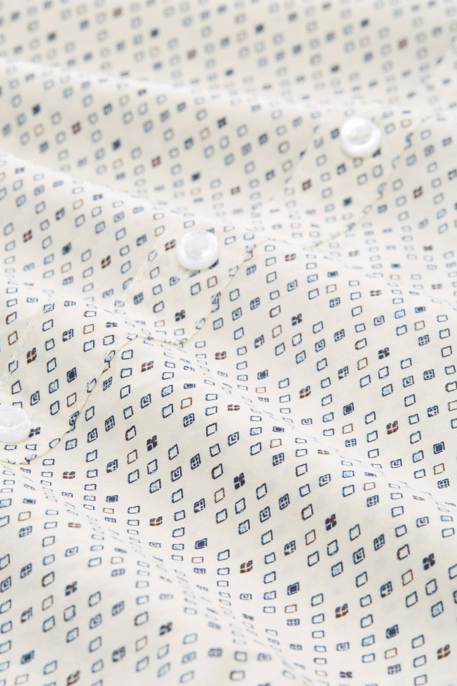 Chemise à manches longues blanche par Tom Tailor, à motifs losanges bleus et marron, avec boutons blancs.
