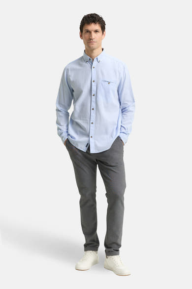 Chemise à manches longues bleue de Tom Tailor, portée avec un pantalon gris et des baskets blanches.