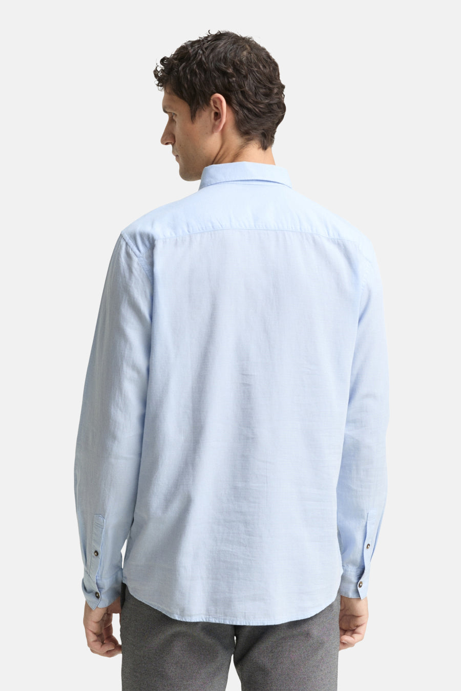 Chemise à manches longues bleue de Tom Tailor, vue de dos, avec pantalon gris.