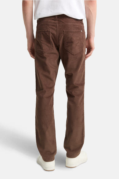 Pantalon coloré brun de Tom Tailor, coupe droite en velours côtelé, porté avec un t-shirt blanc et des baskets blanches.