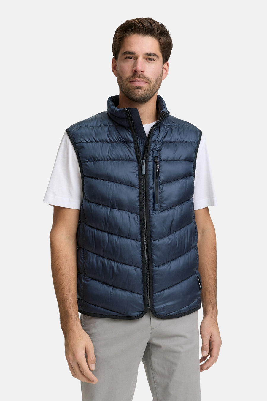 Veste sans manches bleue de Tom Tailor, matelassée avec fermeture éclair, portée sur un t-shirt blanc et un pantalon gris.