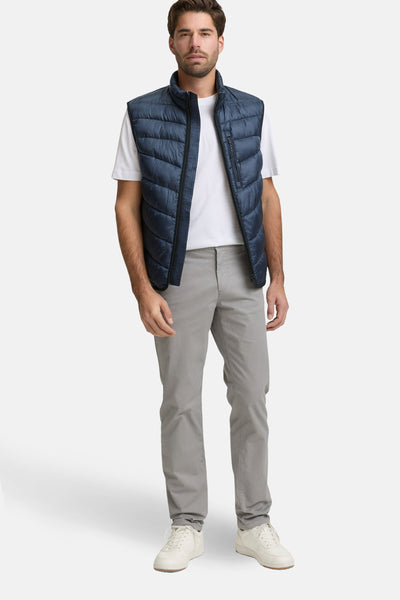 Veste sans manches bleue de Tom Tailor, portée sur un t-shirt blanc et un pantalon gris.