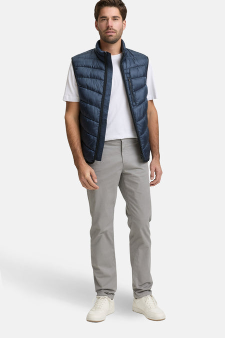 Veste sans manches bleue de Tom Tailor, portée sur un t-shirt blanc et un pantalon gris.