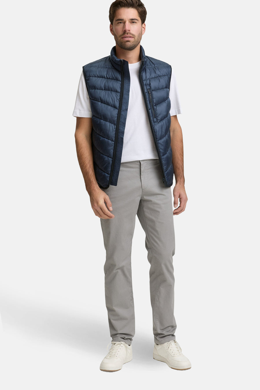 Veste sans manches bleue de Tom Tailor, portée sur un t-shirt blanc et un pantalon gris.