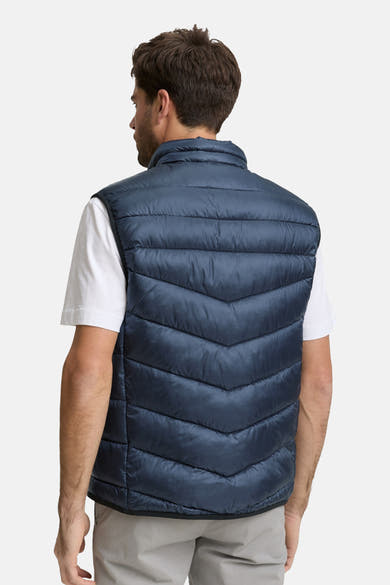 Veste sans manches bleu van Tom Tailor, matelassée avec un motif chevron, portée avec un t-shirt blanc.