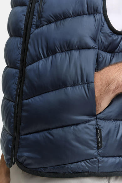 Veste sans manches bleue par Tom Tailor, avec motif matelassé et poche visible.
