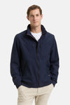 Veste courte bleue de Tom Tailor, avec fermeture éclair et poches zippées, portée sur un t-shirt blanc et un pantalon beige.
