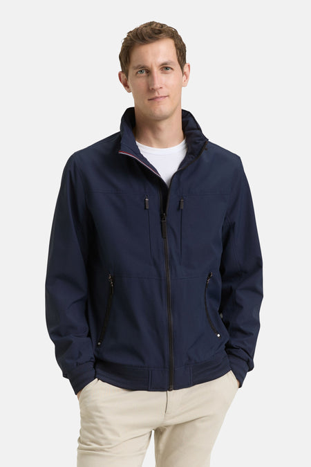 Korte blauwe jas van Tom Tailor, met ritssluiting, zakken met rits en een beige broek.