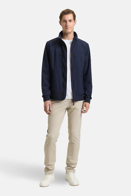 Veste courte bleue de Tom Tailor, avec fermeture éclair, poches zippées et pantalon beige.