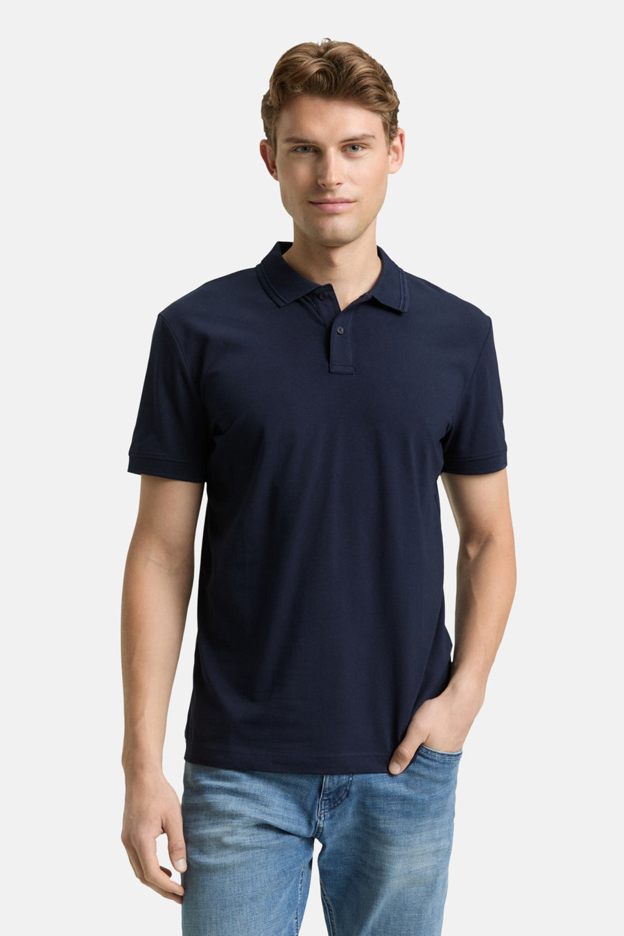 Blauw poloshirt met korte mouwen van Tom Tailor, gedragen met een spijkerbroek en witte sportschoenen.