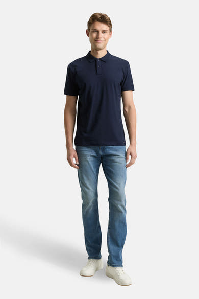 Polo bleu à manches courtes de Tom Tailor, porté avec un jean et des chaussures de sport blanches.