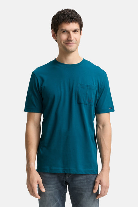 T-shirt à manches courtes turquoise de Tom Tailor, avec poche poitrine, porté avec un jean gris délavé.
