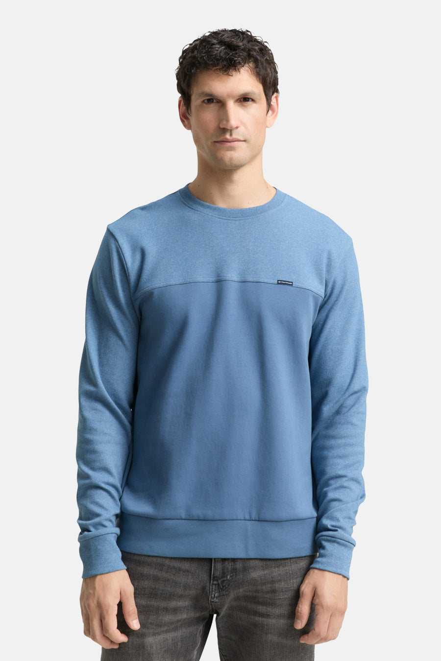 Blauwe sweater van Tom Tailor, gedragen met een donkergrijze jeans en witte sportschoenen.