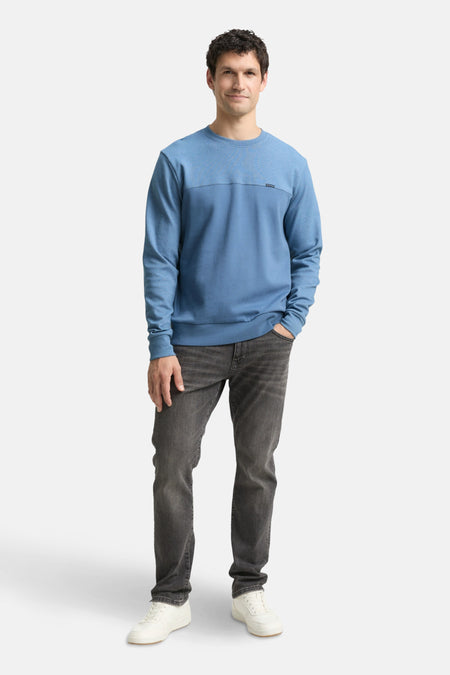 Sweat bleu de Tom Tailor, porté avec un jean gris foncé et des chaussures de sport blanches.