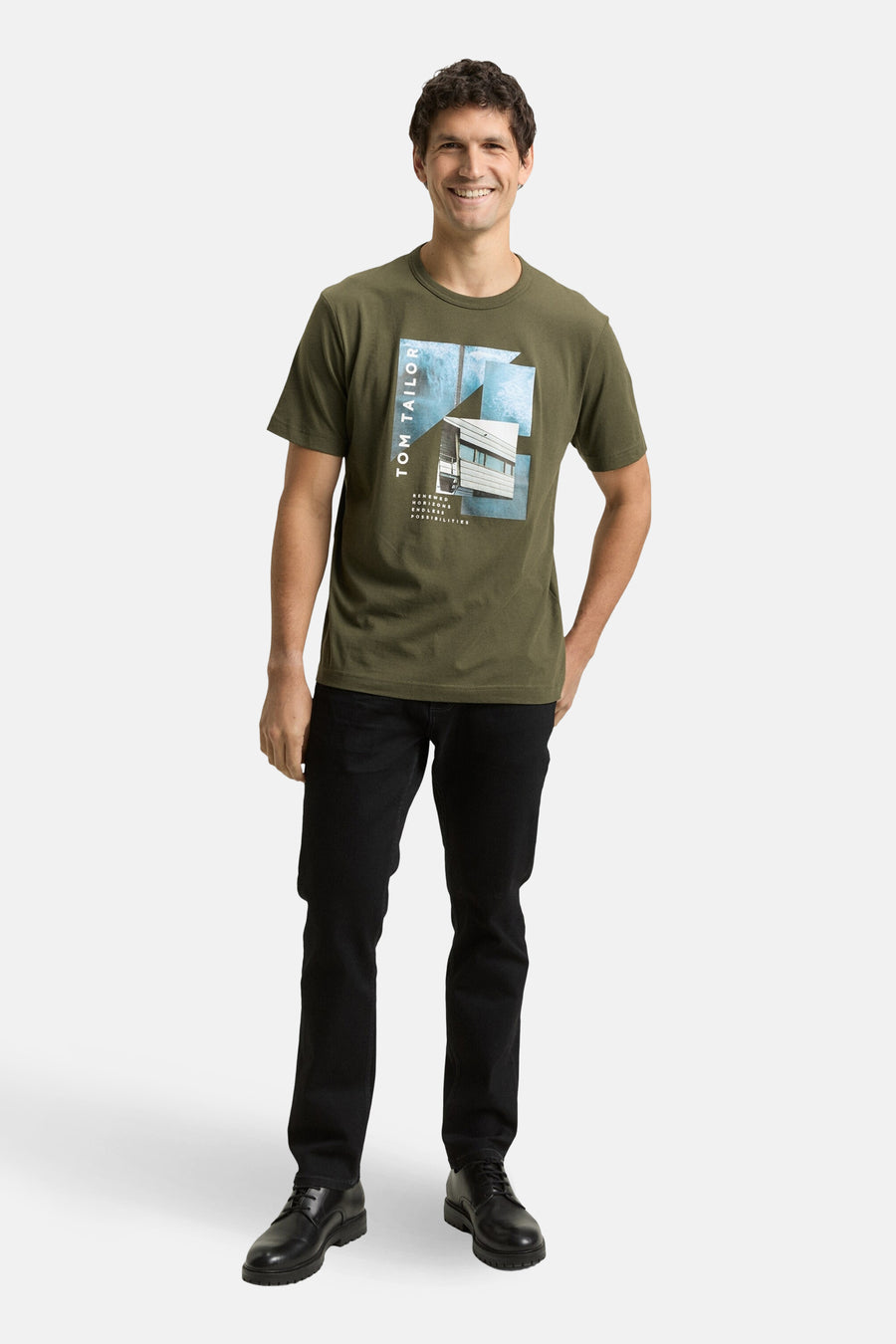 T-shirt kaki à manches courtes de Tom Tailor, avec imprimé graphique sur le devant, porté avec un jean noir et des chaussures habillées.

