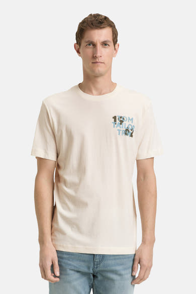 Ecru T-shirt met korte mouwen van Tom Tailor, met een decoratief logo op de borst, gedragen met een blauwe jeans en witte sneakers.