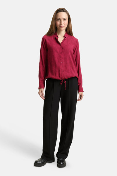Chemisier rose à manches longues de Tom Tailor, texturé à rayures fines, avec cordon de serrage, porté avec un pantalon noir.