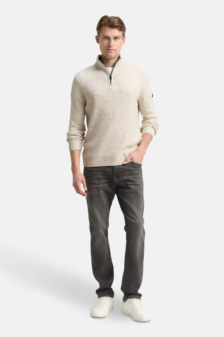 Pull à col roulé écru de Tom Tailor, porté avec un t-shirt blanc et un jean foncé.