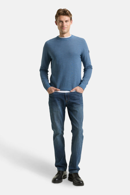 Pull à col rond bleu de Tom Tailor, porté avec un jean et des chaussures noires.