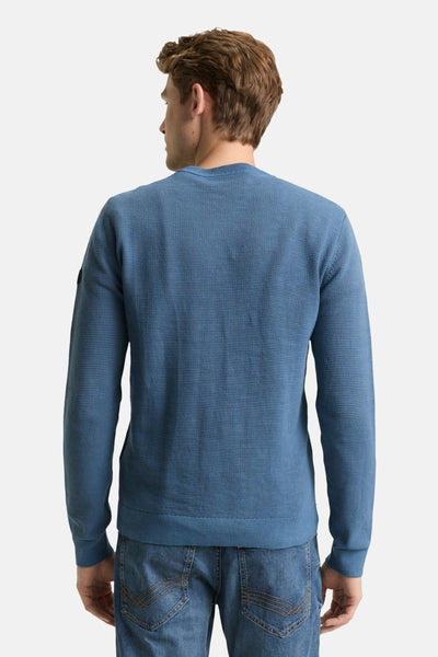 Ronde hals trui blauw van Tom Tailor, in getextureerd breisel, gedragen met een spijkerbroek.