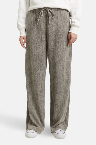 Multikleurige joggingbroek van Tom Tailor, met wijde pijpen en een taille met trekkoord, gedragen met een effen witte trui en witte sneakers.
