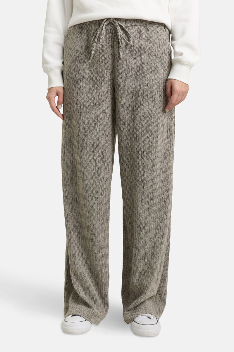 Multikleurige joggingbroek van Tom Tailor, met wijde pijpen en een taille met trekkoord, gedragen met een effen witte trui en witte sneakers.