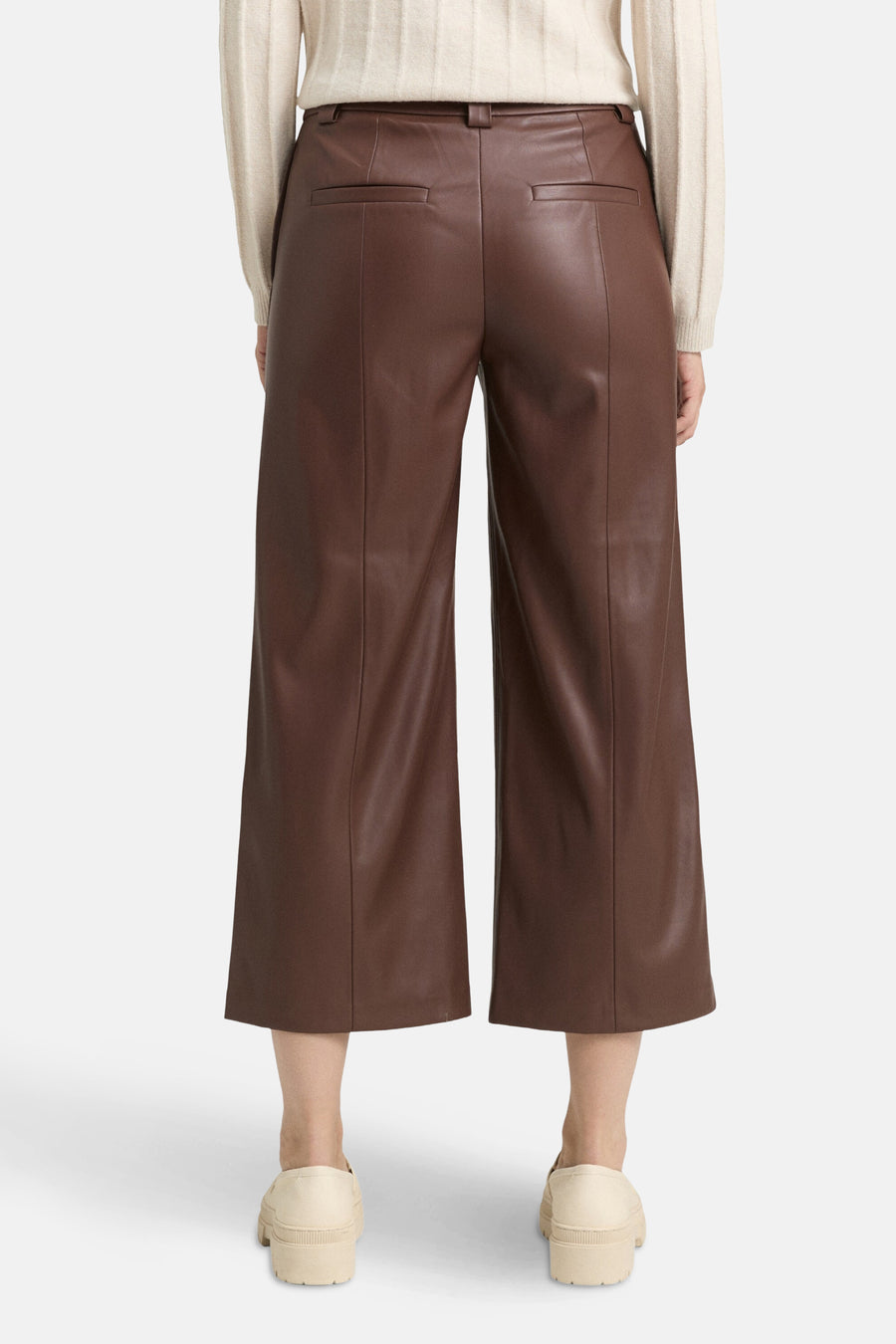 Pantalon large marron en similicuir de Tom Tailor, avec poches arrières et porté avec un pull crème.
