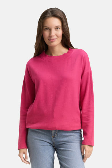 Sweat-shirt rose par Tom Tailor, texture gaufrée, porté avec un jean bleu clair.