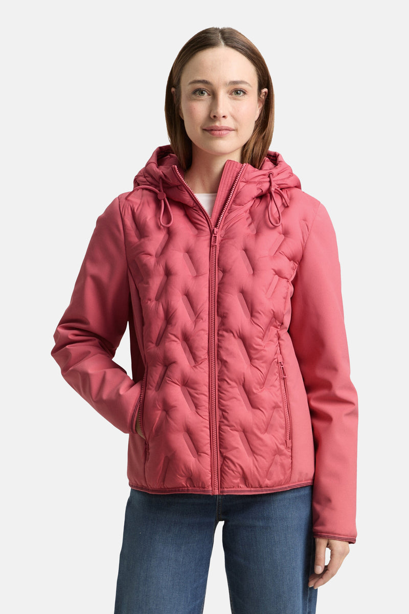 Kort roze jasje van Tom Tailor met een ruitvormige doorgestikte textuur en een capuchon. Gedragen met een blauwe jeans en zwarte laarzen.