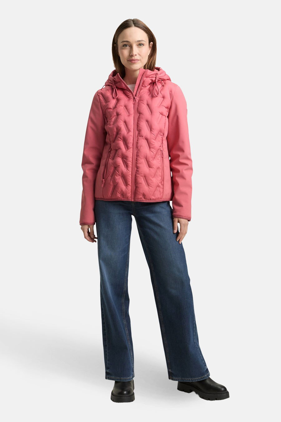 Veste courte rose by Tom Tailor avec une texture matelassée à losanges et un capuche. Porté avec un jean bleu et des bottes noires.