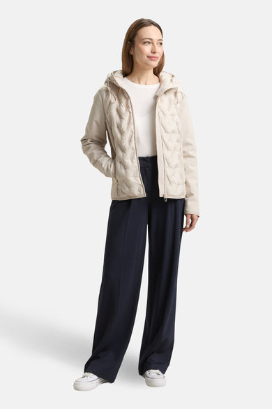 Veste courte beige de Tom Tailor, avec capuche, motif matelassé et portée avec un pantalon large marine et des baskets blanches.