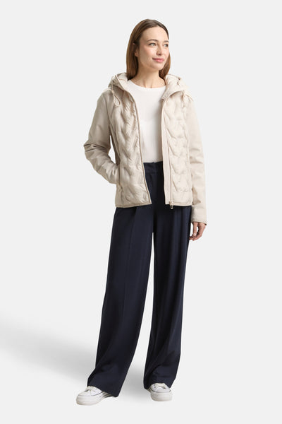 Veste courte beige de Tom Tailor, avec capuche, motif matelassé et portée avec un pantalon large marine et des baskets blanches.