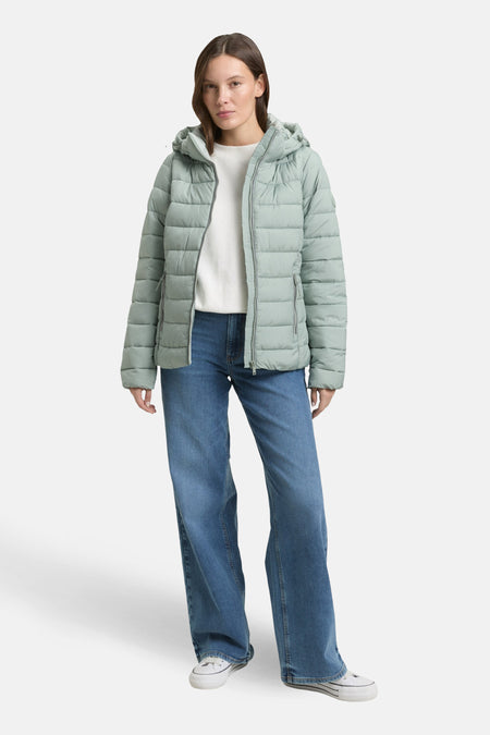 Veste courte verte de Tom Tailor, avec capuche et fermeture éclair, portée avec un jean bleu et des baskets blanches.