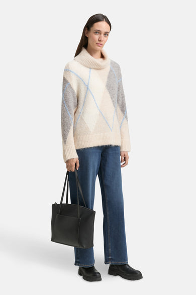 Pull à col roulé multicolore de Tom Tailor, avec motif losanges et porté avec un jean bleu et des bottines noires.
