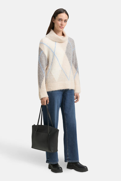 Pull à col roulé multicolore de Tom Tailor, avec motif losanges et porté avec un jean bleu et des bottines noires.
