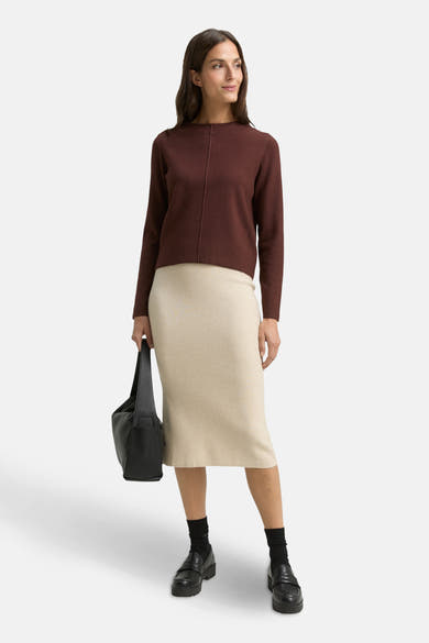 Bruine ronde trui van Tom Tailor, gedragen met een beige rok, een zwarte handtas en lage schoenen.