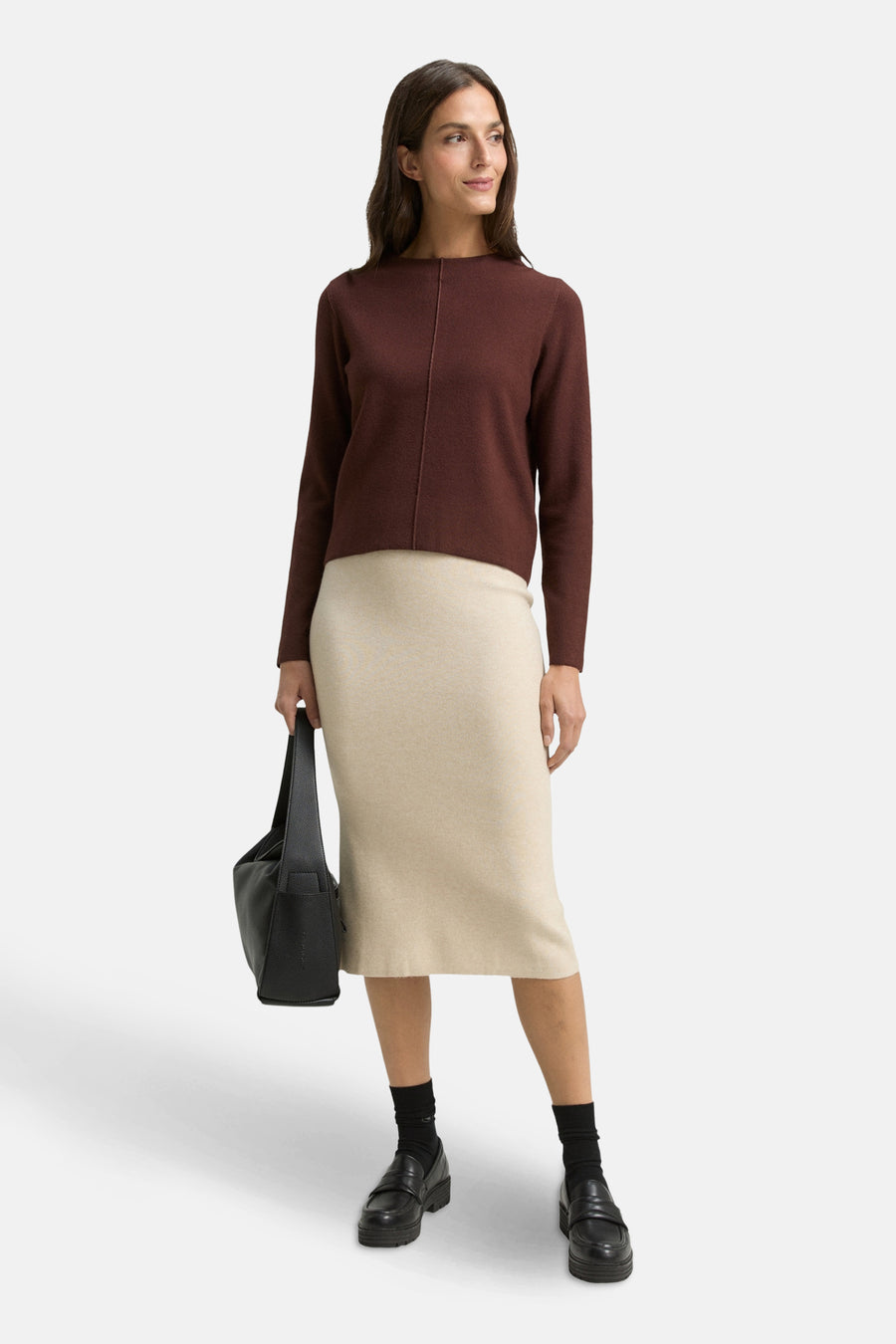 Bruine ronde trui van Tom Tailor, gedragen met een beige rok, een zwarte handtas en lage schoenen.