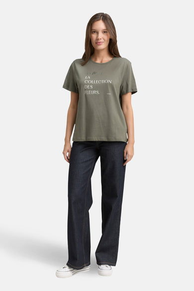 T-shirt à manches courtes kaki de Tom Tailor, imprimé texte, porté avec un jean large et des baskets blanches.
