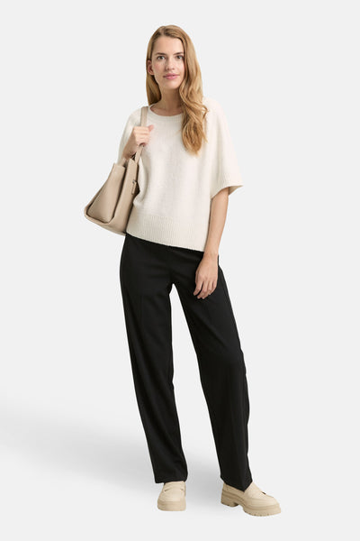 Pull à col rond blanc de Tom Tailor, porté avec un pantalon noir et des mocassins à plateforme beiges.
