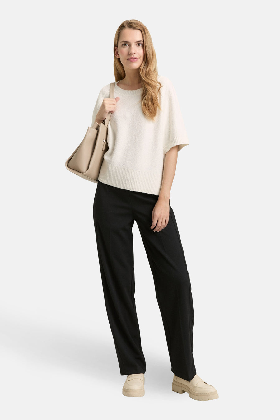 Pull à col rond blanc de Tom Tailor, porté avec un pantalon noir et des mocassins à plateforme beiges.
