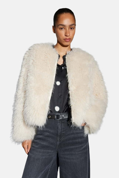 Veste courte beige de OPUS, portée avec un chemisier à pois et un jean taille haute.