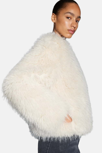Veste courte beige d'OPUS en fausse fourrure douce, portée avec un jean sombre.