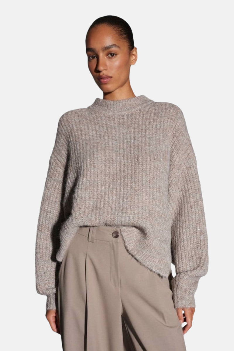 Pull à col rond taupe d'OPUS, en maille côtelée avec des détails pailletés discrets, porté avec un pantalon beige à plis.