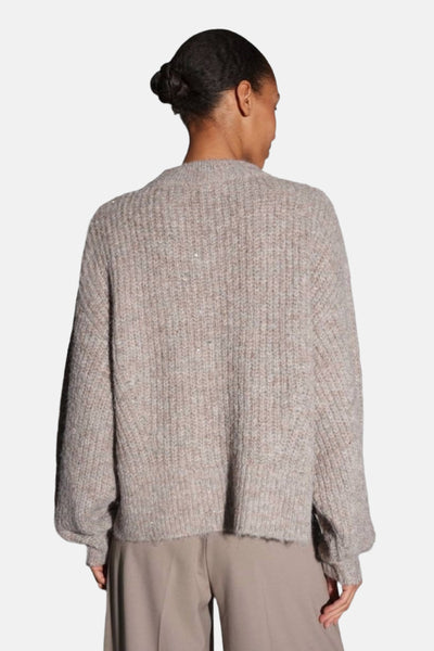 Pull taupe à col rond par OPUS, en maille côtelée texturée avec des reflets brillants, porté avec un pantalon beige.