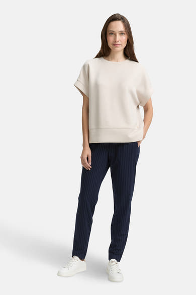 Blauwe gestreepte broek van Tom Tailor, gedragen met een gebroken witte top en witte sneakers.