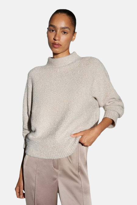 Pull col rond beige d'OPUS, à texture bouclée, porté avec un pantalon satiné couleur crème.