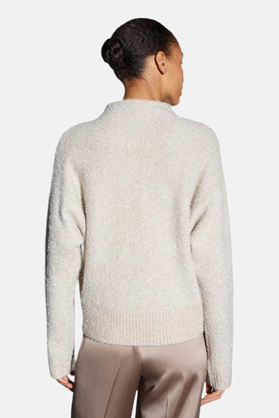 Pull col rond beige de OPUS, en maille texturée, porté avec un pantalon satiné.
