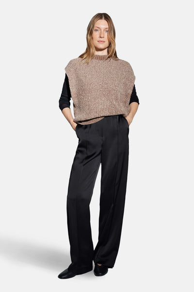 Débardeur taupe en maille d'OPUS, porté sur un haut noir à manches longues, avec un pantalon noir.
